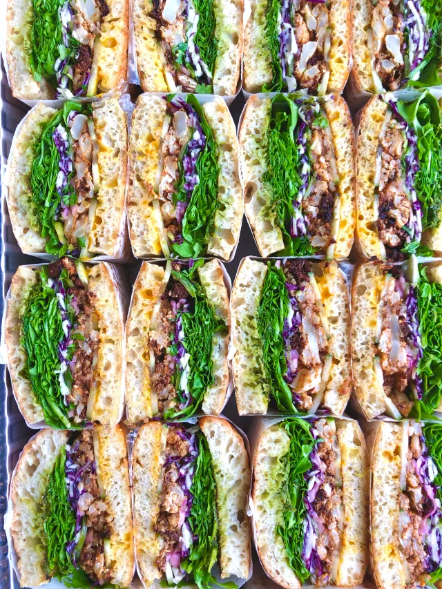 Paper-wrapped sandwich halves standing in rows, seen from above