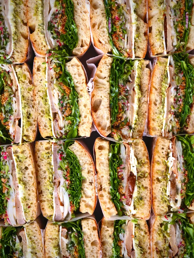 Rows of paper-wrapped sandwich halves packed tight, seen from above
