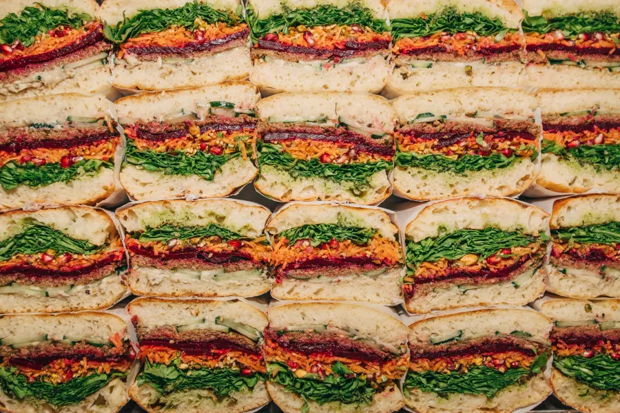 Rows of sandwich halves with red, orange and green layers, packed edge to edge, seen from above