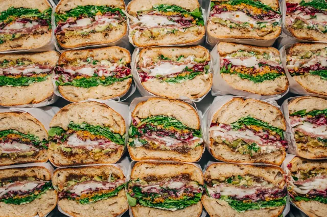 Rows of paper-wrapped sandwich halves packed edge to edge, seen from above