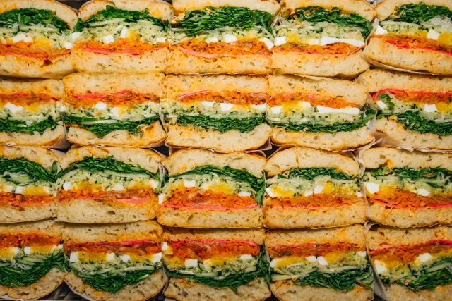 Rows of sandwich halves with bright orange and green layers, seen from above
