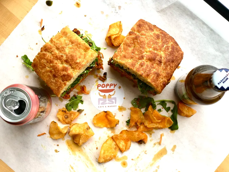 Sandwich halves, golden chips and drinks on Poppy-branded paper, photographed from above