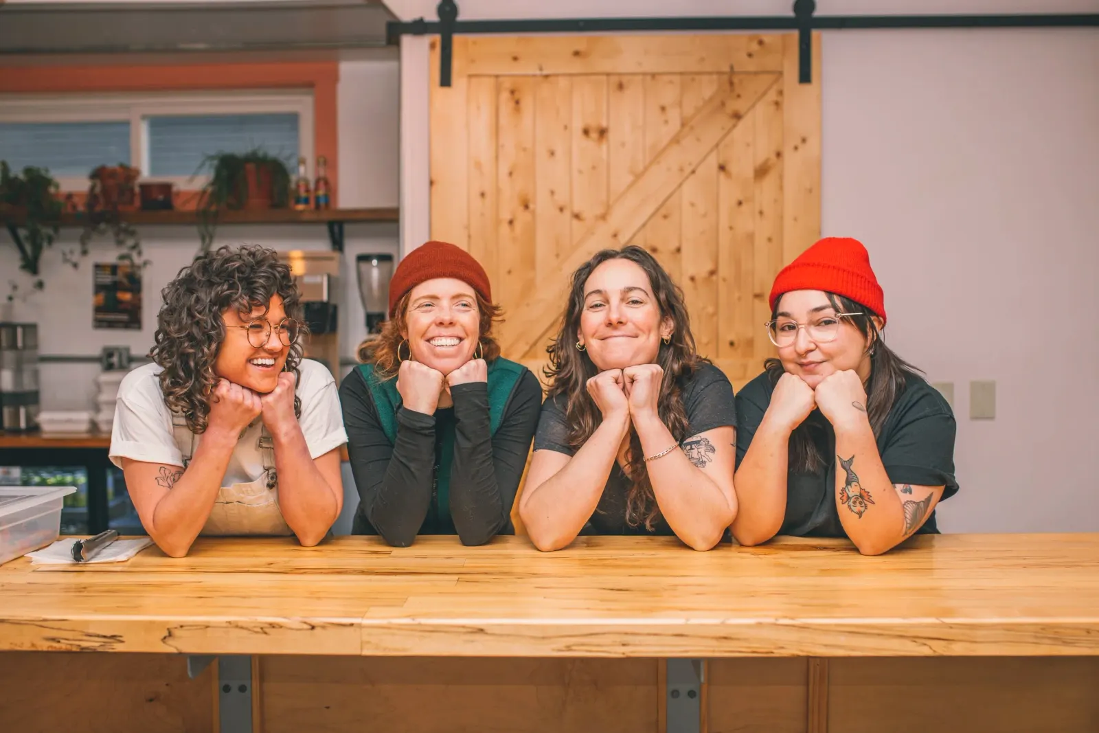 Four people smiling and leaning on Poppy’s wooden counter