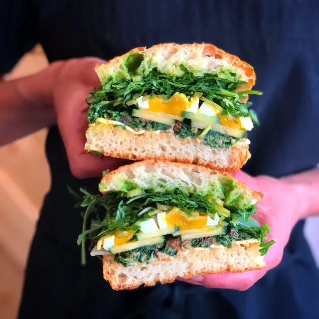 Two sandwich halves held close to the camera against a navy apron